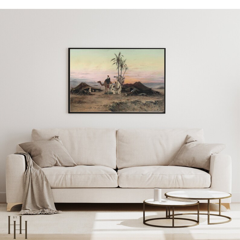 May include: A framed painting depicting a desert scene with two camels, people, and tents. The painting is set against a backdrop of a pink and orange sunset.