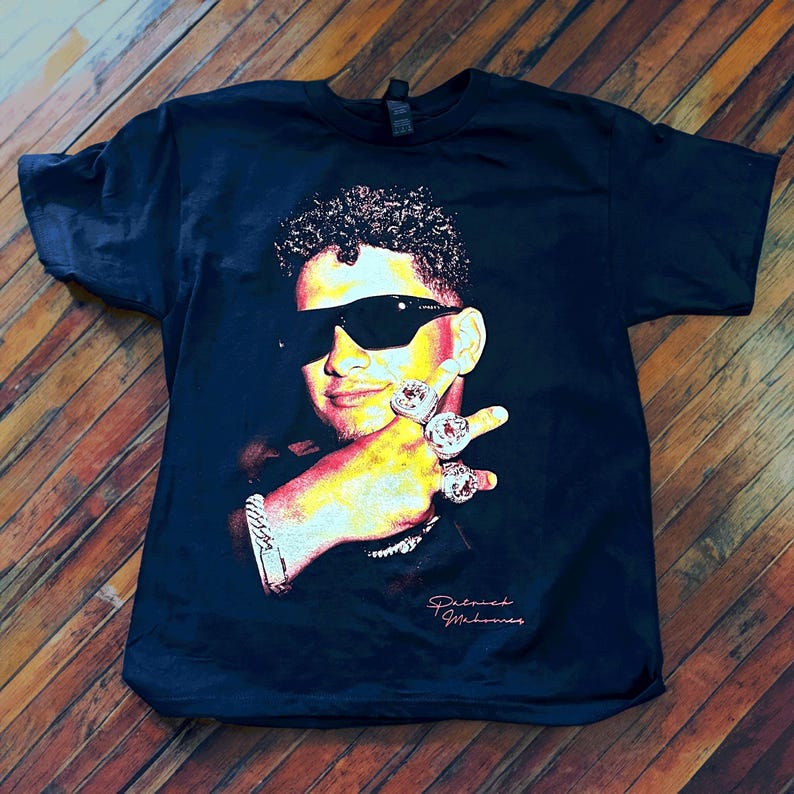 May include: Black t-shirt with a colorful image of a man wearing sunglasses and multiple rings on his fingers. The text "Patrick Mahomes" is printed on the bottom of the shirt.