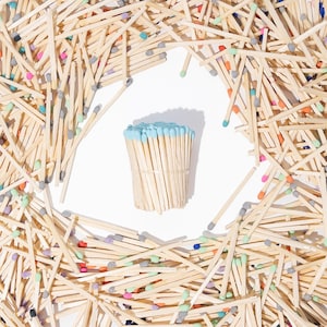 May include: A close-up image of a bundle of colorful matchsticks with blue tips. The matchsticks are arranged in a circle around a bundle of blue-tipped matches.
