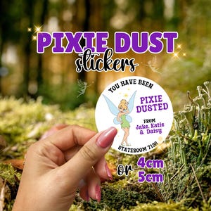 May include: A round white sticker featuring a cartoon fairy with blonde hair and blue wings. The text reads: YOU HAVE BEEN PIXIE DUSTED FROM Jake, Katie & Daisy STATEROOM 7138. The sticker is available in 4cm or 5cm sizes as indicated by the text.