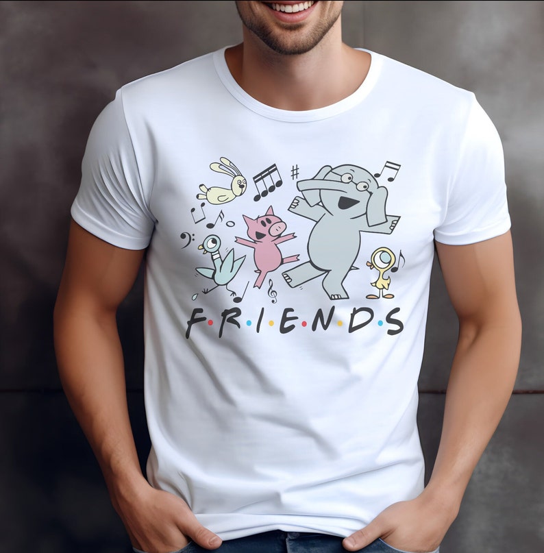 May include: White t-shirt with a cartoon illustration of a group of animals dancing and playing music. The text "FRIENDS" is printed below the animals.
