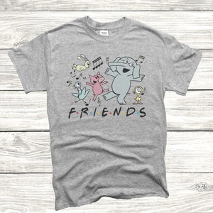 May include: Gray t-shirt with a cartoon illustration of a pig, elephant, and birds dancing with musical notes. The text "FRIENDS" is printed below the illustration.