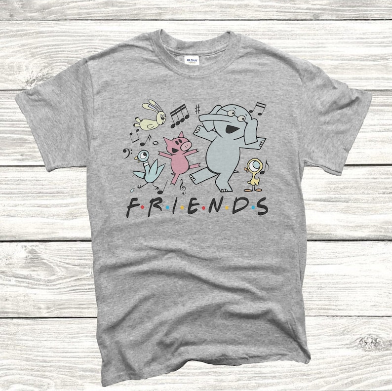 May include: Gray t-shirt with a cartoon illustration of a pig, elephant, and birds dancing with musical notes. The text "FRIENDS" is printed below the illustration.