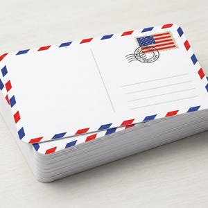 May include: A stack of white postcards with red and blue diamond borders. Each postcard features an American flag stamp and lines for writing. The postcards are stacked neatly on a light-colored surface.