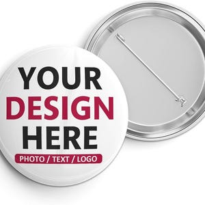 Könnte beinhalten: Zwei weiße runde Ansteckbuttons mit Metallnadel-Rückseite. Ein Button zeigt den Text "YOUR DESIGN HERE" in Schwarz und Burgunderrot, darunter "PHOTO / TEXT / LOGO". Der andere Button zeigt die Rückseite mit einer Nadel.