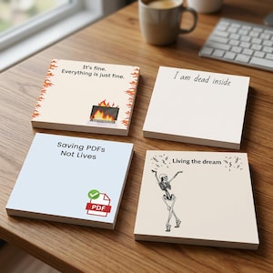 May include: Four square sticky note pads with humorous office-themed designs. One features a laptop on fire with the text 'It's fine. Everything is just fine.', another says 'I am dead inside', one shows a PDF icon with 'Saving PDFs Not Lives', and one shows a dancing skeleton with 'Living the dream'.