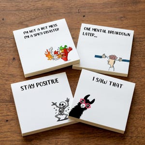May include: Four square white sticky note pads with black text and illustrations. One features a chilli pepper with the text I'M NOT A HOT MESS I'M A SPICY DISASTER. Another shows a brain with ONE MENTAL BREAKDOWN LATER. A third has a skeleton with STAY POSITIVE. The last shows a llama with I SAW THAT.