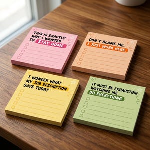 Op de afbeelding: Vier vierkante memoblokjes in roze, oranje, geel en lichtgroen. Elk blokje bevat een checklist met vijf vakjes en humoristische tekst: THIS IS EXACTLY WHY I WANTED TO STAY HOME, DON'T BLAME ME. I JUST WORK HERE, I WONDER WHAT MY JOB DESCRIPTION SAYS TODAY, en IT MUST BE EXHAUSTING WATCHING ME DO EVERYTHING.