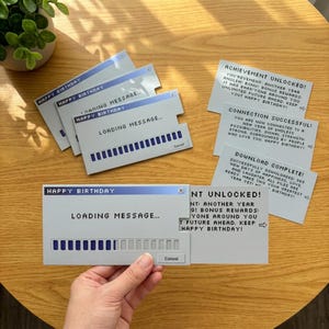 Puede incluir: Un conjunto de tarjetas de cumpleaños rectangulares diseñadas como ventanas emergentes de computadora. Las tarjetas presentan una barra de título azul con el texto HAPPY BIRTHDAY, una barra de carga y textos como LOADING MESSAGE y ACHIEVEMENT UNLOCKED.