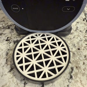 May include: A white plastic drip tray with a geometric pattern of triangles. The tray is designed to catch drips from a kitchen appliance.