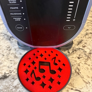 Op de afbeelding: Ronde rode basis met een zwart muzieknootontwerp. De basis is voor een slushmachine.