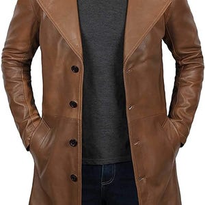 Puede incluir: Una gabardina de cuero marrón con un diseño largo de un solo botón y un cuello de muesca. La gabardina tiene un cierre de botón y varios bolsillos.
