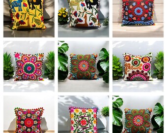 May include: Nine colorful embroidered throw pillows with pom-pom trim. The pillows feature various floral and animal designs.