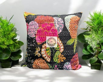 May include: Black cotton cushion cover with a floral pattern in pink, green, and orange. The cushion cover has a white stitched design and the text "REEMKAROLI INDIA HANDMADE ITEM" in a circle.