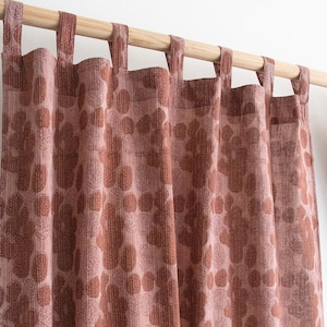 Op de afbeelding: Roze en bruine gordijnpanelen met bloemenpatroon die aan een houten roede hangen. De gordijnen hebben een herhalend patroon van gestileerde bladeren en bloemen in roze en bruine tinten. De stof heeft een getextureerde uitstraling.