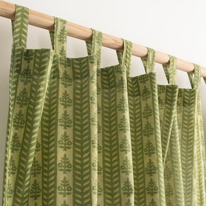 Puede incluir: Cortinas verdes y crema con un patrón de hojas repetido. Las cortinas cuelgan de una barra de madera con lazos de tela. La tela tiene una apariencia texturizada y el diseño es vertical.