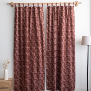 Puede incluir: Dos cortinas a juego de color granate con un estampado floral repetido. Las cortinas cuelgan de una barra de madera. El estampado floral es de un tono m&aacute;s oscuro de granate. Las cortinas est&aacute;n frente a una pared blanca.