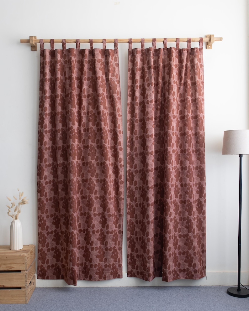 Puede incluir: Dos cortinas a juego de color granate con un estampado floral repetido. Las cortinas cuelgan de una barra de madera. El estampado floral es de un tono m&aacute;s oscuro de granate. Las cortinas est&aacute;n frente a una pared blanca.