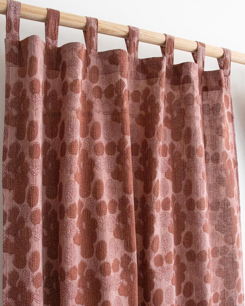Puede incluir: Paneles de cortinas con estampado floral rosa y marr&oacute;n colgados de una barra de madera. Las cortinas presentan un patr&oacute;n repetido de hojas y flores estilizadas en tonos rosa y marr&oacute;n. La tela tiene un aspecto texturizado.