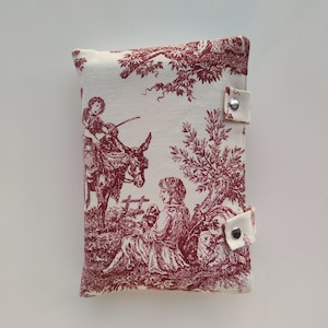 May include: A white fabric pouch with a red toile pattern featuring a shepherdess, a donkey, and a tree. The pouch has two silver snap closures.