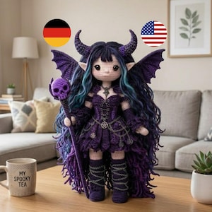 May include: A handmade crochet doll with a gothic theme. The doll has purple hair, horns, and wings, and wears a purple dress with chain accents. It holds a staff with a skull on top. The doll is on a wooden table.