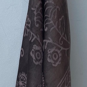 May include: A brown bandana with a geometric pattern. The bandana is folded and tied at the top.