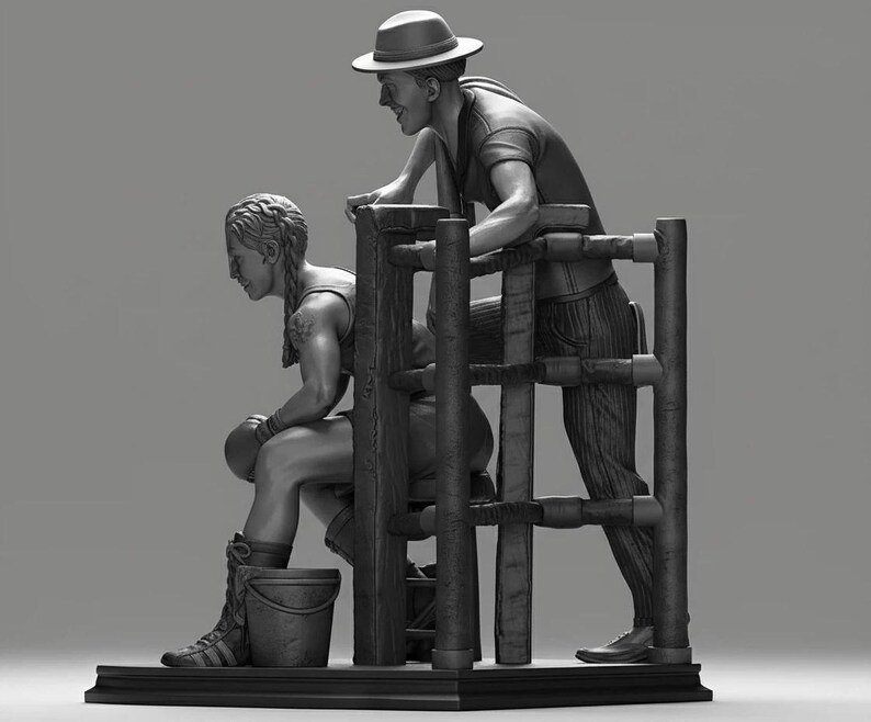 May include: A monochrome sculpture depicting a boxer and their coach. The boxer is seated, wearing gloves and boots, with a bucket nearby. The coach, in a hat, leans over a wooden structure, watching. The sculpture is detailed.