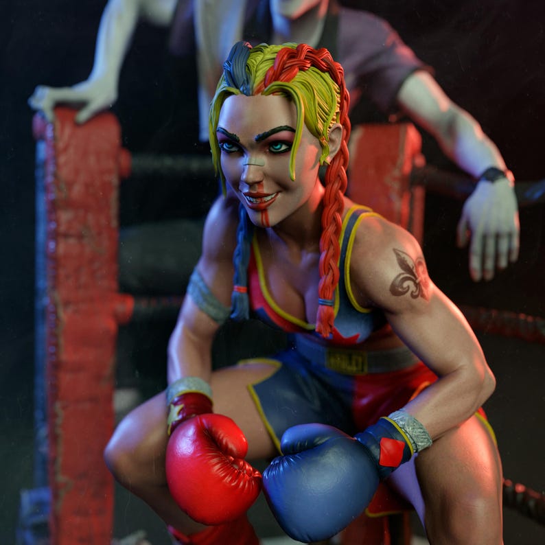 May include: A detailed figurine of a female boxer in a boxing ring. She wears red and blue boxing attire, red and blue gloves, and has multi-coloured braided hair. A tattoo is visible on her arm. Another figure is in the background.