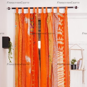 Może przedstawiać: Pomarańczowe i kremowe zasłony w stylu patchwork z kwiatowym wzorem. Zasłony są wykonane z recyklingowanych sari i wiszą na czarnym karniszu.