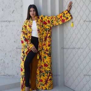 May include: A long, yellow floral kimono with red and green accents. The kimono features a vibrant pattern of flowers and birds. The sleeves are wide and flowing, and the garment is adorned with yellow tassels. The text "FABRICFABS CRAFTS" is visible.
