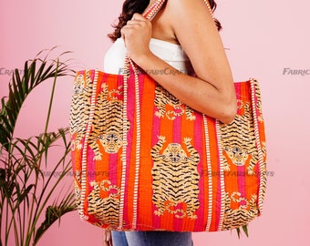 May include: A large orange and pink tote bag with a tiger print. The bag has a wide strap and is made of a quilted fabric.