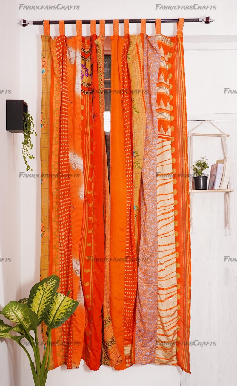 Puede incluir: Cortinas de patchwork naranja y crema con un patr&oacute;n floral. Las cortinas est&aacute;n hechas de saris reciclados y est&aacute;n colgadas de una barra de cortina negra.