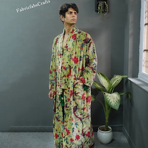 May include: A green velvet robe with a floral print featuring birds and flowers. The robe has a long, flowing silhouette and a sash tie at the waist.