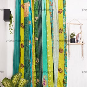 Puede incluir: Un conjunto de cortinas de patchwork verde y azul hechas de saris reciclados. Las cortinas est&aacute;n colgadas de una barra y est&aacute;n compuestas por diferentes piezas de tela cosidas juntas. La tela es una mezcla de seda y algod&oacute;n y tiene una variedad de patrones y colores.