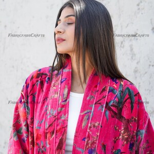 May include: A pink velvet kimono with a floral and bird print. The kimono has a white lining and a shawl collar.