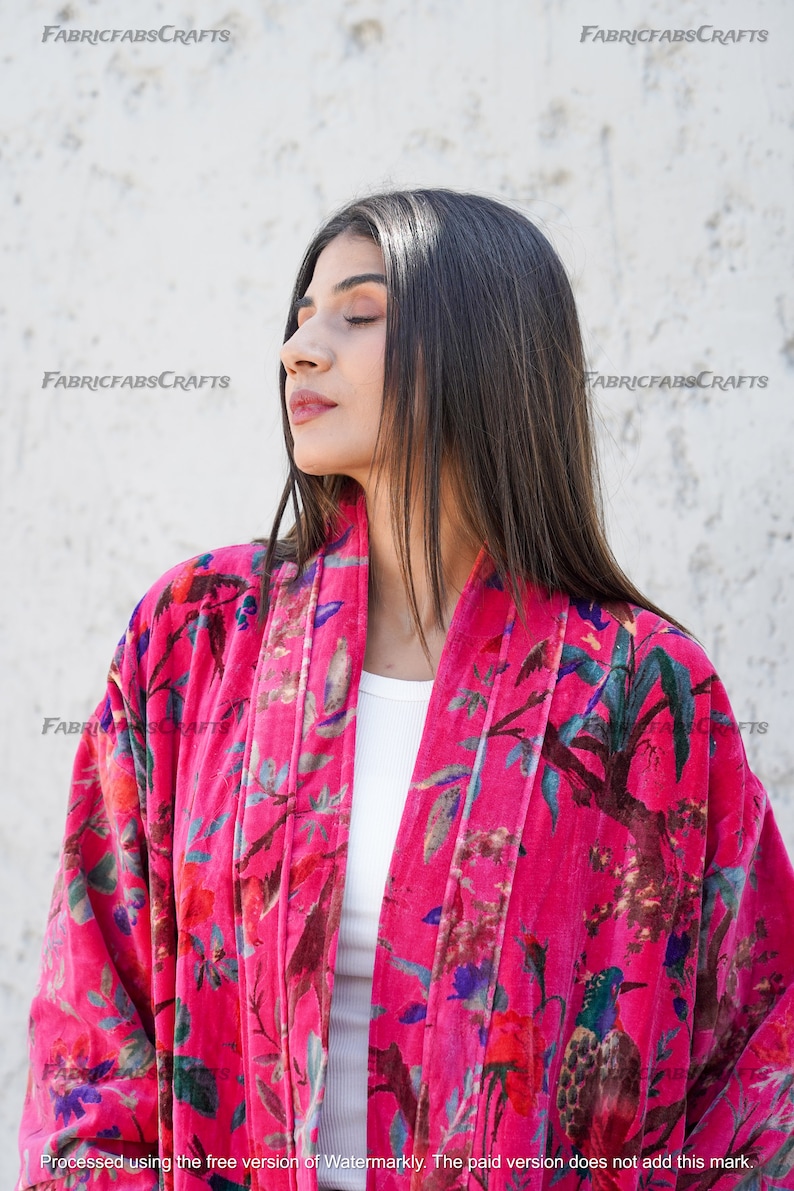 May include: A pink velvet kimono with a floral and bird print. The kimono has a white lining and a shawl collar.