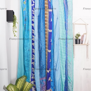 Puede incluir: Un conjunto de cortinas de seda azules y turquesas con una variedad de patrones, incluyendo dise&ntilde;os florales y geom&eacute;tricos. Las cortinas est&aacute;n colgadas de una barra de metal y est&aacute;n hechas de saris reciclados.