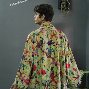 May include: A green velvet robe with a floral and bird print. The robe has a high collar and long sleeves. The fabric is soft and luxurious.