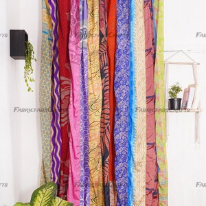Puede incluir: Una cortina colorida hecha de saris reutilizados, con una variedad de patrones y colores, incluyendo morado, rosa, azul, rojo, amarillo y verde. La cortina est&aacute; colgada de una barra y tiene aproximadamente 2,7 metros de largo.