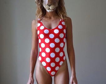 Puede incluir: Una mujer con un traje de baño de lunares rojos y blancos con una máscara de león.