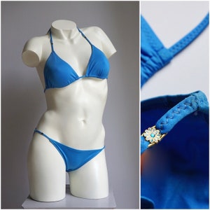 May include: A bright blue bikini top and bottom with a floral accent on the strap. The bikini is made of a smooth, stretchy fabric.
