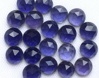 May include: A collection of sixteen round, faceted blue gemstones arranged in a cluster. Each stone features a geometric rose-cut pattern with triangular facets that converge at a central point, displaying deep indigo and violet hues throughout.