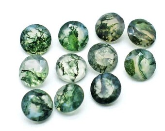 May include: A collection of ten round, faceted moss agate gemstones. Each stone features a translucent, pale base with distinct, dark green, fern-like inclusions that create unique, organic patterns within the polished, circular surfaces.
