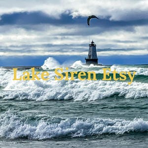 May include: A white lighthouse stands tall against a stormy blue sky with white clouds.  The lighthouse is surrounded by choppy blue water with white waves crashing against the shore.  The text "Lake Siren Etsy" is superimposed on the image.