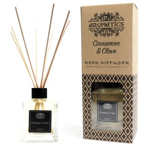 May include: Aromatics Cinnamon & Clove reed diffuser. The clear glass bottle contains a light-colored liquid and reeds. The black label reads "Cinnamon & Clove" and "200ml". The product is displayed with its decorative cardboard box.