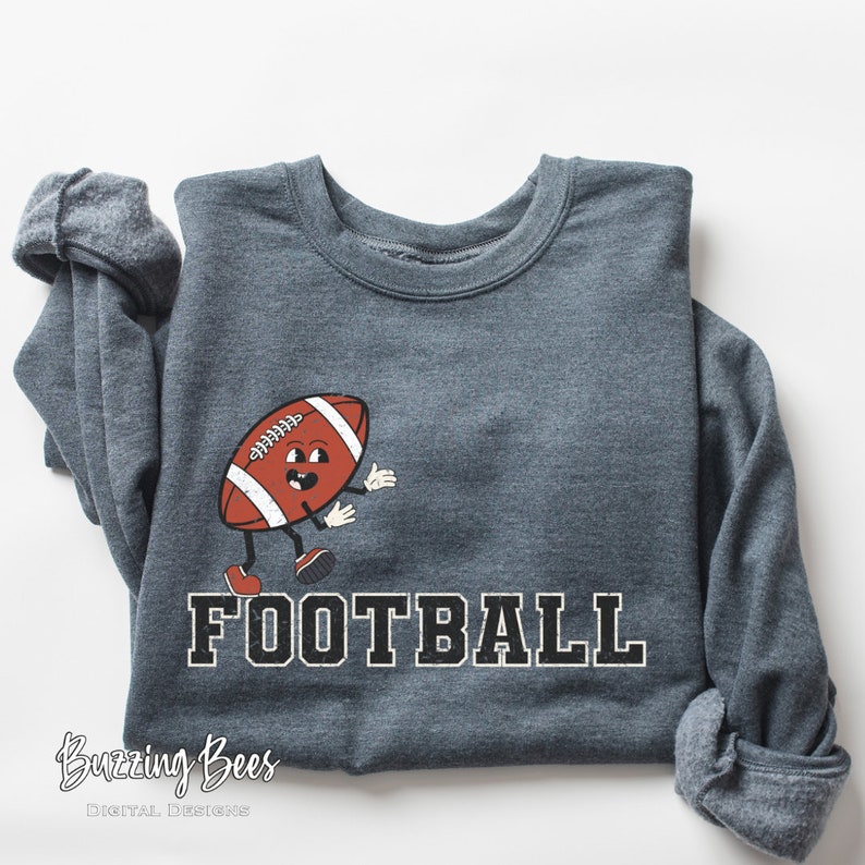 May include: A dark gray sweatshirt with a cartoon football character and the word "FOOTBALL" printed in white with a black outline.