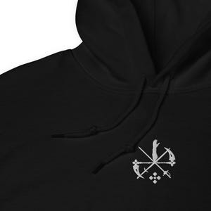 May include: Black hoodie with a white embroidered emblem. The emblem features crossed scythes, swords, and a hand, with a geometric design below. The hoodie has a drawstring and a kangaroo pocket.