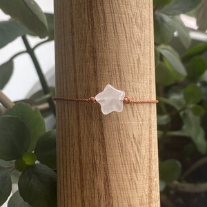 May include: A simple bracelet with a clear star-shaped crystal charm on a brown cord.