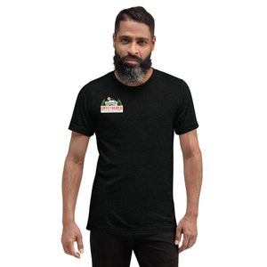 May include: A dark gray t-shirt with a small graphic on the chest. The graphic features a mountain scene with the word "UNTETHERED" in a rectangular frame. The shirt is short-sleeved and has a crew neck.