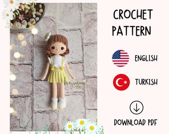 May include: Crochet pattern for a doll with brown hair, a white dress, a yellow skirt, and white shoes. The pattern is available in English and Turkish. Download the PDF.